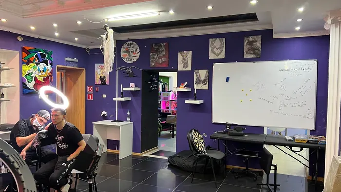 Интерьер тату студии Only Tattoo: рабочая зона с кушеткой, кольцевой лампой и эскизами на стенах