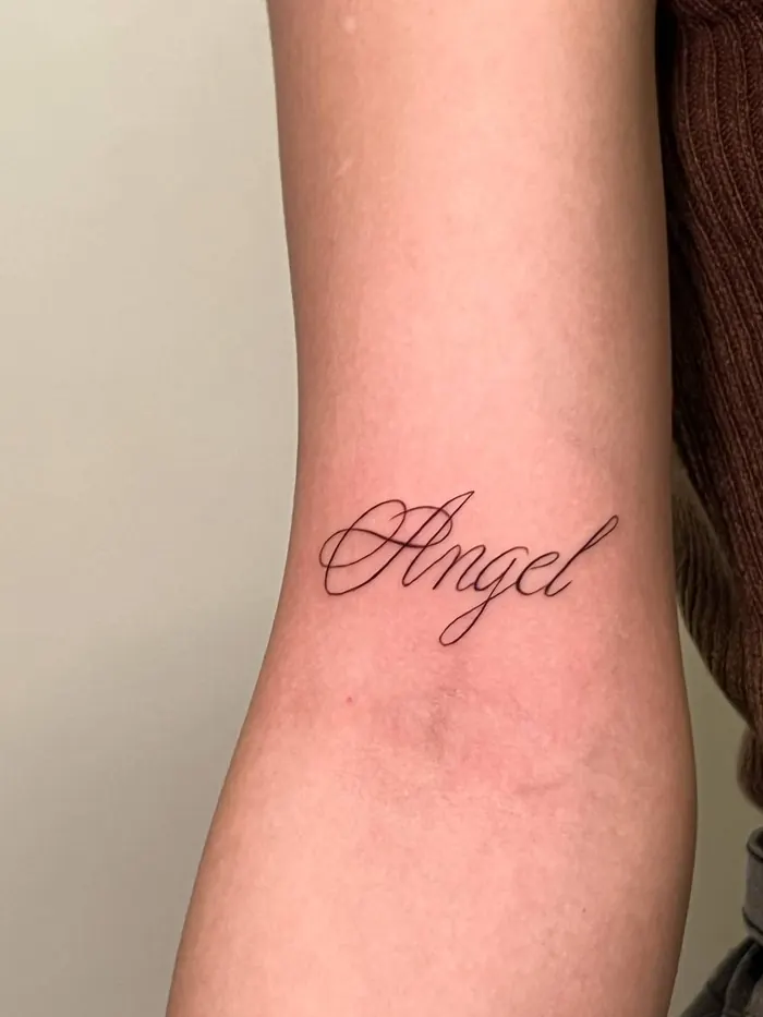 Тонкая каллиграфическая надпись Angel на предплечье